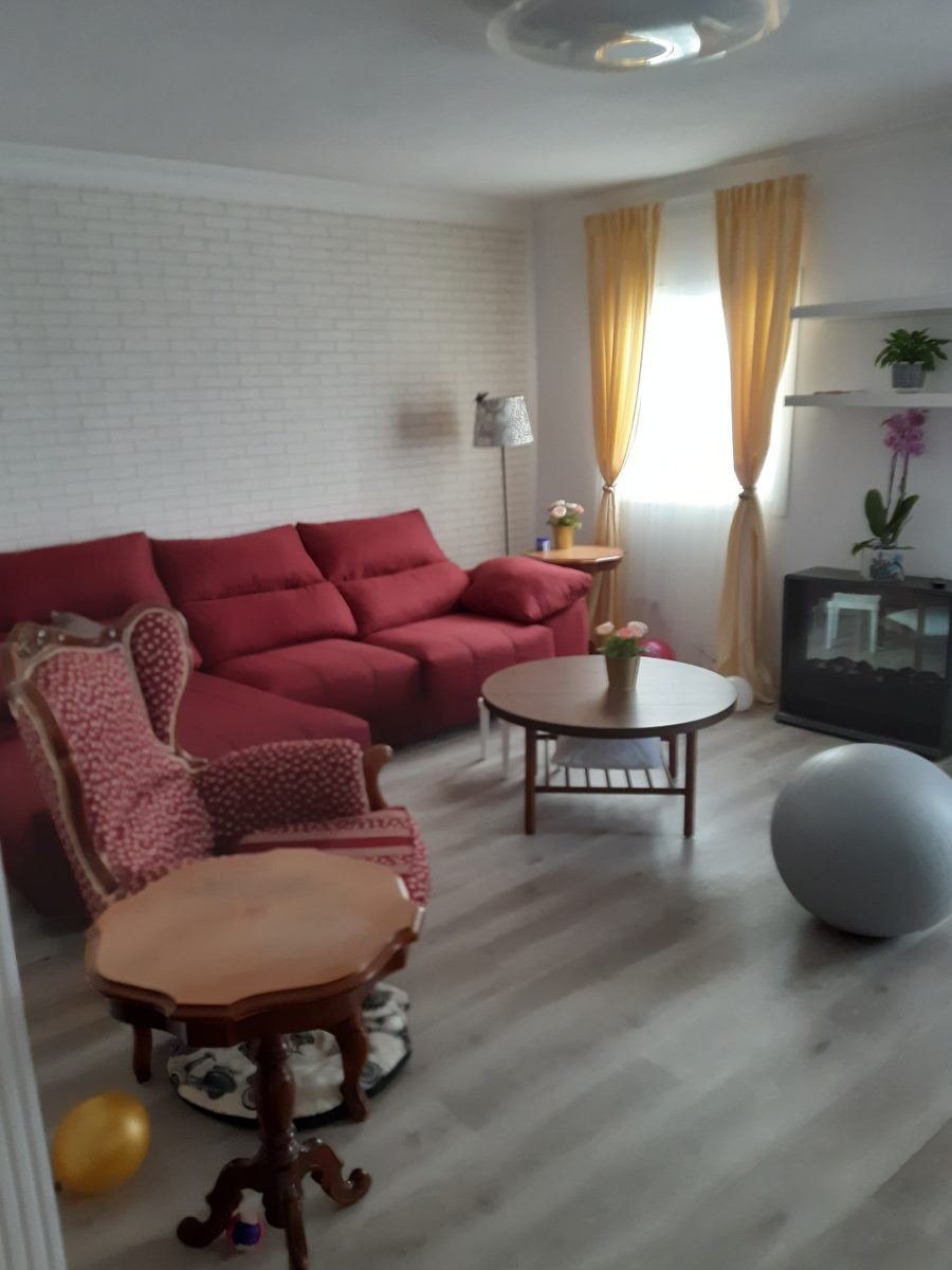 Salón después de la reforma integral, con pared de ladrillo blanco