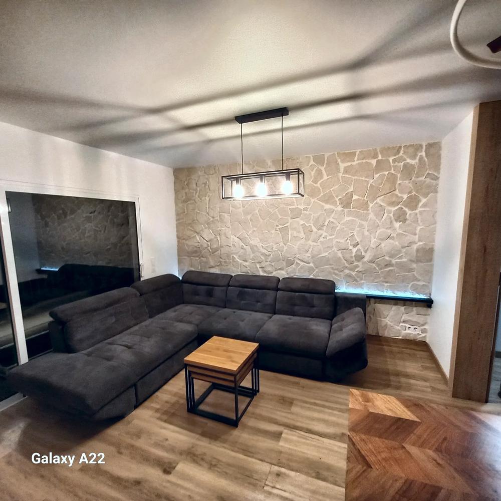 Salón con pared de piedra natural terminado tras una reforma integral
